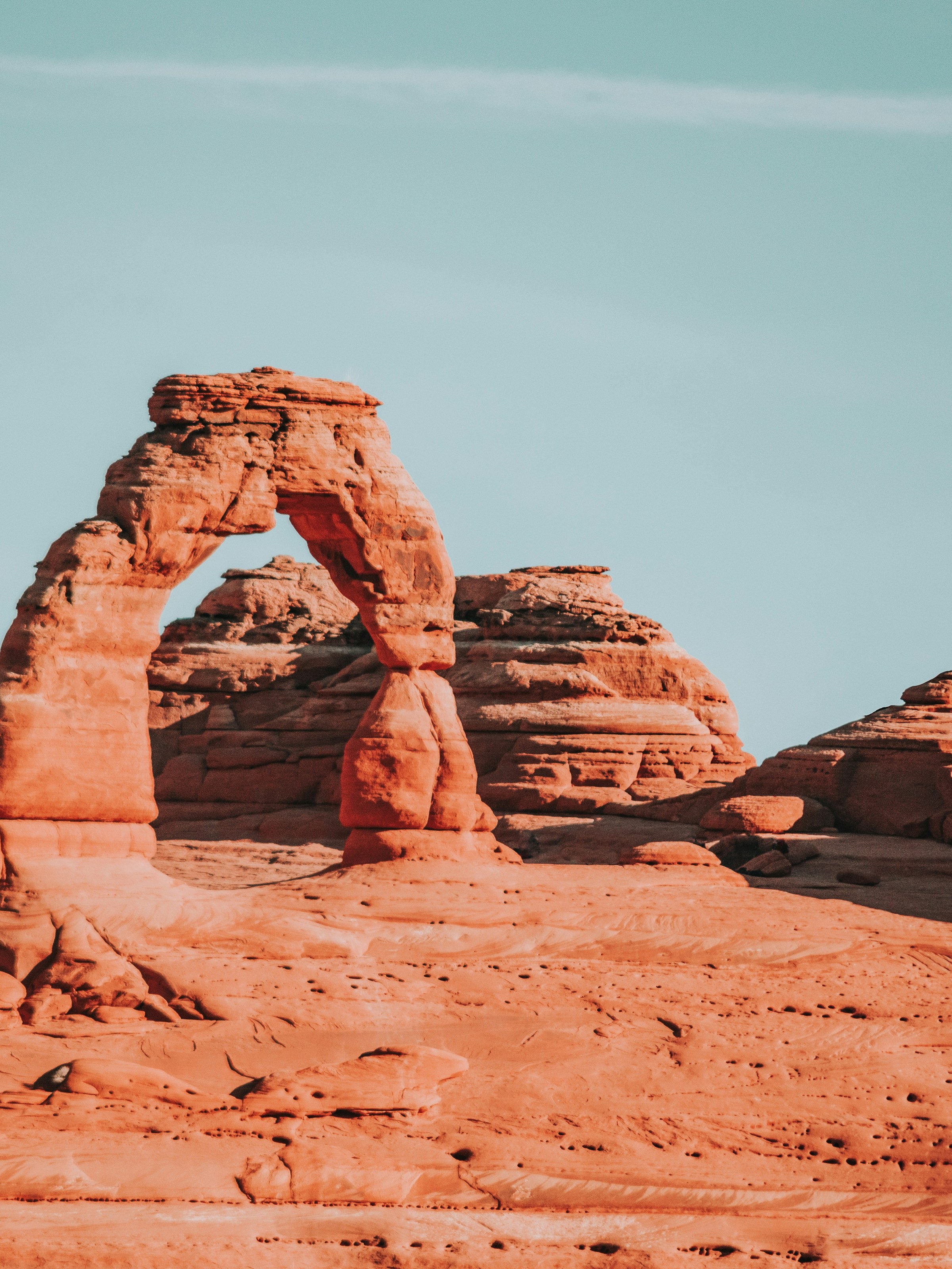 Red rock arch under a clear blue sky in a desert landscape.